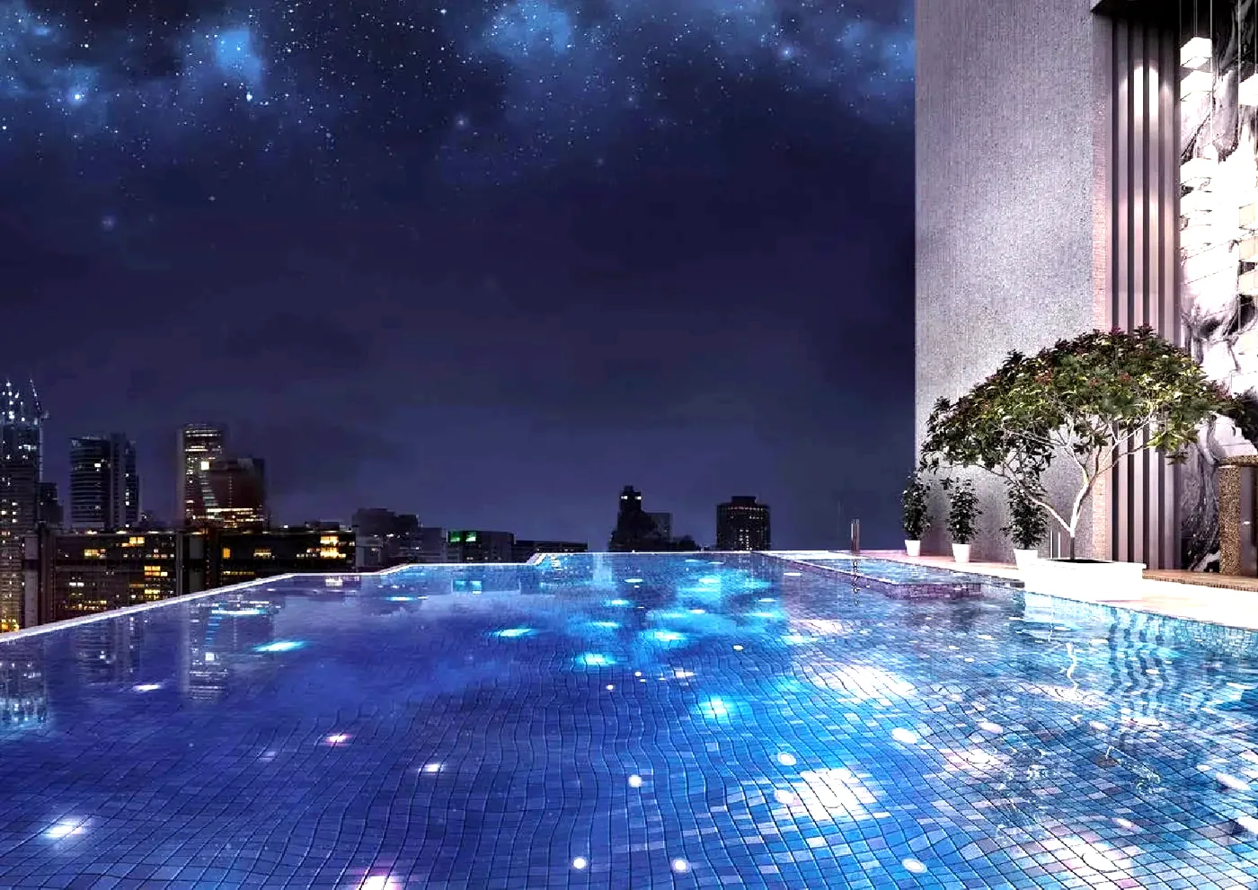 The lit infinity pool at The Manor at night, with the Kuala Lumpur skyline beyond it